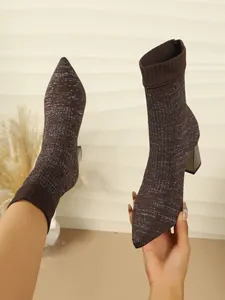 Brown knitted sock boots with sparkling details, pointed toe, and block heel shown in detail