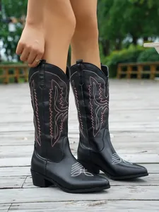Detail von schwarzen Cowboystiefeln mit weißer Stickerei und spitzer Zehenkappe.