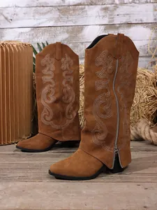 Detailed view of brown suede knight boots with elegant white embroidery patterns.