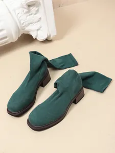 Detailed view of dark green stretch knit sock boots with a stylish brown chunky mid-heel