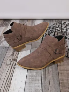 Detail view of brown pointed toe ankle boots with low block heel and side buckle.