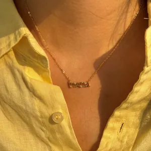 Gros plan d'un collier MAMA doré avec cristaux sur une chemise jaune
