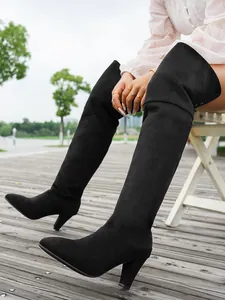 Detailed side view of black suede pointed-toe over-the-knee stretch boots with chunky high heels.