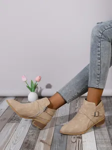 Detail of beige suede pointed-toe ankle boots with side zipper and block heel.