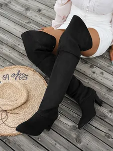Close-up of black suede pointed-toe over-the-knee boots on wooden deck