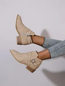Detailed side view of beige pointed toe ankle boots with block heel and buckle strap