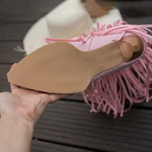 Close-up detail showing the non-slip sole and thin heel of pink tassel high-top fashion boots.
