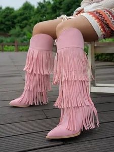 Close-up detail of stylish pink high heel boots featuring layered long fringe design