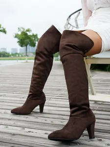 Detailed side view of elegant brown suede pointed-toe over-the-knee high heel boots
