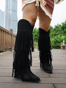 Detailed view of black suede high boots with tiered long fringe and stiletto heel.