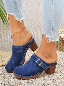 Vista dettagliata di sabot in camoscio blu con tacco largo e fibbia con jeans
