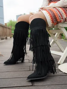 Detailed view of black suede fringe boots with tiered tassels and stiletto heels