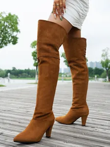 Close-up of brown suede over-the-knee boots with pointy toe and high chunky heel
