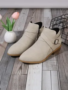 Elegant beige suede pointed-toe ankle boots with side zipper and decorative buckle strap