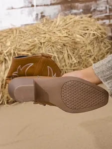 Détail macro d'une botte de cowboy brodée avec semelle antidérapante et talon bloc stable