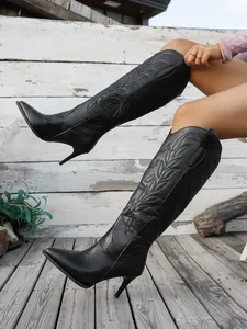 Side view of black pointed-toe stiletto boots with intricate leaf embroidery detail.