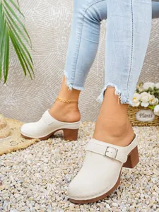 Primo piano di eleganti sabot color crema da donna con tacco a blocco e fibbia decorativa