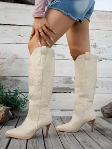Detail view of cream embroidered high-top boots with pointed toe and stiletto heel