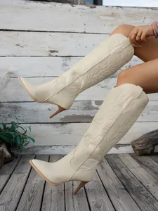 Detailed view of cream embroidered western knee-high boots with a stylish stiletto heel