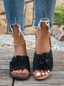 Vue détaillée des sandales compensées noires avec applique florale et motifs ajourés pour femmes
