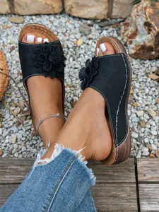 Vue détaillée des sandales compensées noires pour femmes avec décor de fleurs
