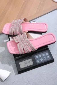 Detailed view of pink rhinestone flat slide sandals being weighed on a digital scale