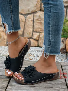 Détail des sandales compensées noires avec fleurs et mesure du talon de 4,5 cm.