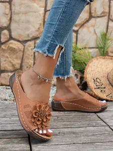 Vue détaillée des mules compensées pour femmes avec fleur décorative et design ajouré