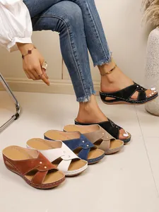 Detail view of women's peep-toe wedge sandals with rivet accents and cross straps.