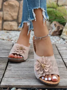 Détail de sandales compensées beige avec décoration florale 3D et découpes ajourées