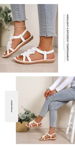 Detail shot of white Bohemian flat sandals with elegant flower decorations on model