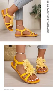 Close-up of yellow Bohemian flat sandals with floral details on model's feet