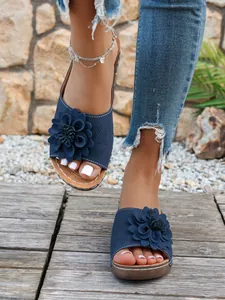 Vue rapprochée de sandales compensées à fleurs bleu marine avec semelles à plateforme
