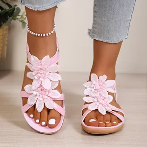 Pink bohemian flat sandals with decorative 3D flowers and crisscross straps
