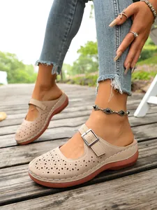 Detailed shot of beige hollow floral pattern clogs featuring a stylish buckle strap