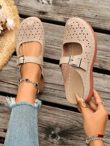Detailed view of beige hollow-out wedge sandals with adjustable buckles and floral cutouts