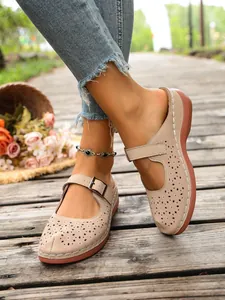Detailed view of beige hollowed-out wedge slippers featuring decorative buckles and flowers