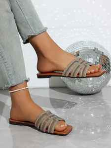 Close-up of stylish summer flat sandals featuring multiple sparkling rhinestone straps