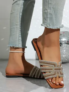 Close-up of stylish women's flat slide sandals with sparkling rhinestone straps