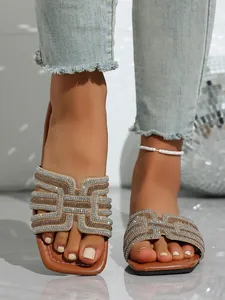Detail view of sparkling rhinestone flat slide sandals with elegant geometric pattern.