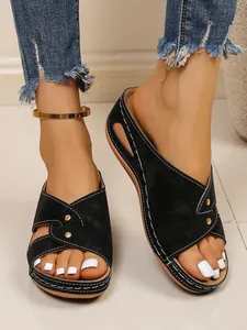 Detailed view of women's black wedge sandals with rivets and stylish cross strap design.