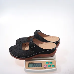 Close-up showing the lightweight design of black hollow wedge mules on a scale