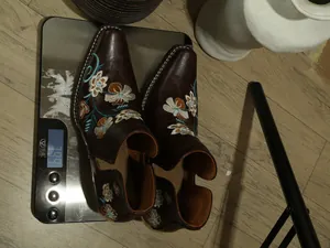 Vista detallada de botines western marrones bordados con tacón ancho en una báscula