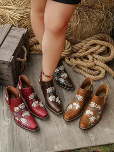 Botines occidentales vintage con bordado floral en varios colores sobre madera rústica