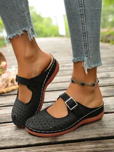 Detailed close-up view of black floral cutout platform clogs with adjustable silver buckle strap