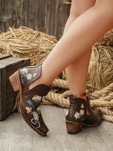 Detalle de botines occidentales marrones con bordado floral y tacones anchos para mujer