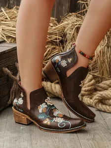 Detalle de botas western vintage marrones con bordados florales y tacón grueso.