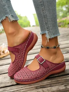 Detailed view of burgundy hollow-out floral wedge mules with adjustable buckle strap.
