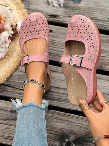 Detailed shot of pink floral hollow-out wedge slippers with a metal buckle strap