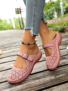 Detailed view of pink hollowed-out wedge slippers with buckle strap on wooden path.